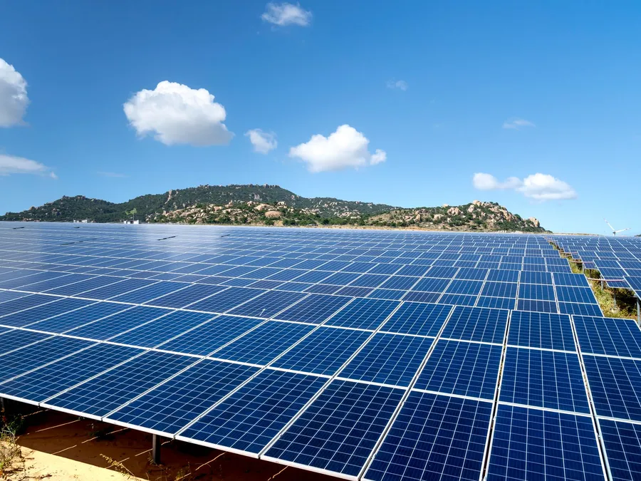 Ground-mounted solar panels on a green farm, illustrative photograph