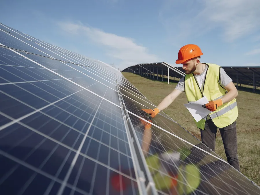 Engineer inspecting solar panels in an agricultural setting, illustrative photograph