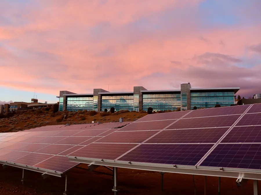 Solar panels beside a modern commercial building at sunset, illustrative photograph