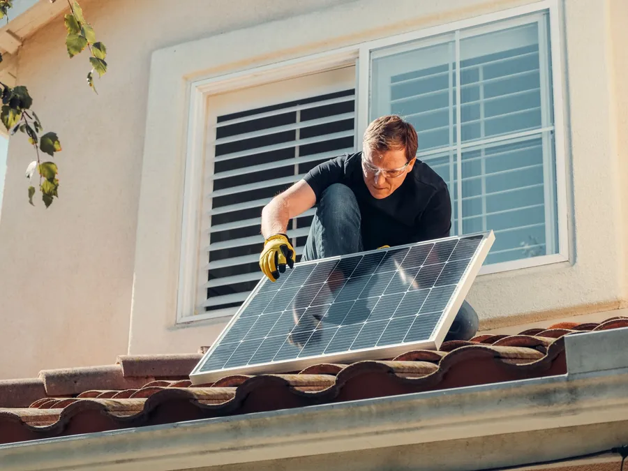 Technician wearing gloves installing rooftop solar panels, illustrative photograph